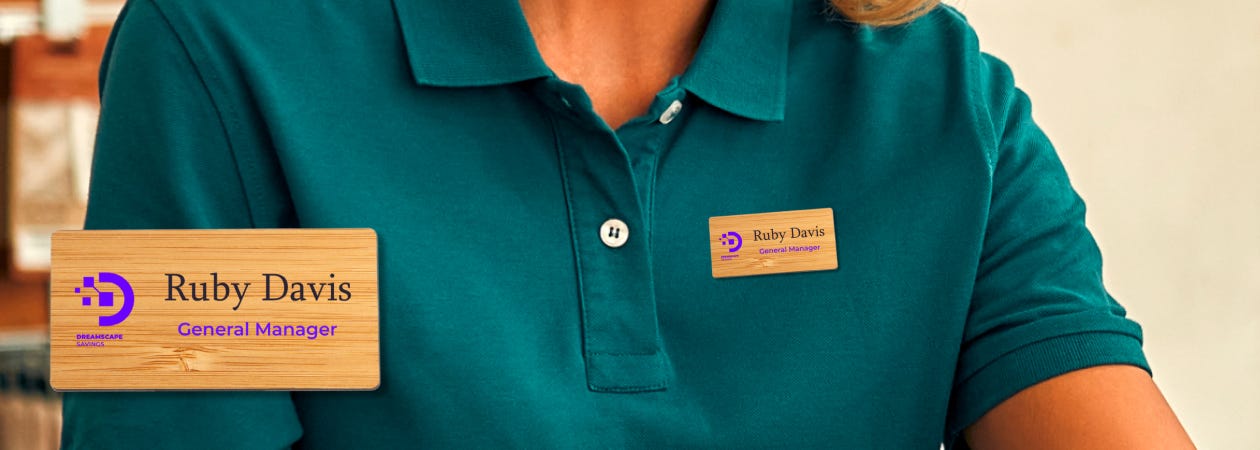 A woman in a green shirt wearing a bamboo wooden name badge