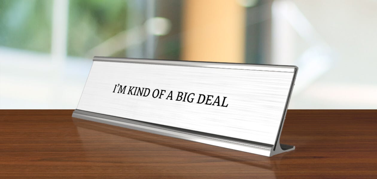 A metal name plate on a desk with a sign that reads "I am kind of a big deal."