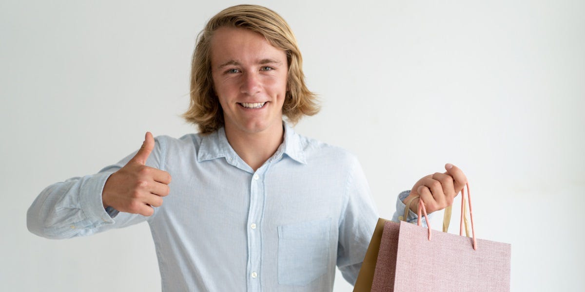 A man with shopping bags, showing a thumbs up gesture, indicating his satisfaction with his purchases.