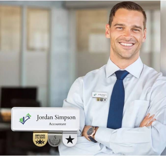 A smiling man in a business shirt with his name badge and medallions, exudes confidence and professionalism.